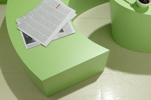 Detailaufnahme einer grünen Sitzbank mit Papierdokumenten und Tischausschnitt mit Kaffeetasse