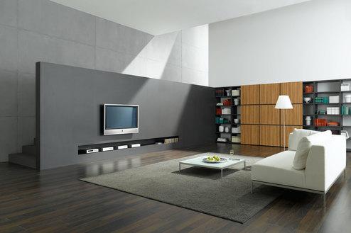 Offene Wohnraumimpression mit grauer TV-Trennwand zur Treppe und Einbauregal aus Holz und weißem Sofa